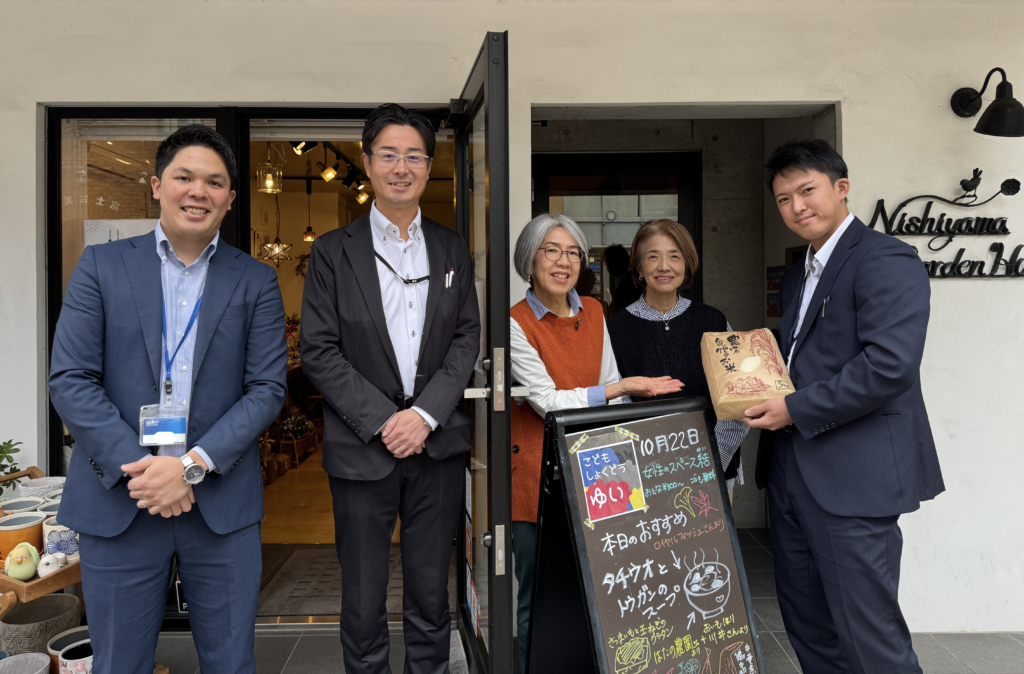 西武信用金庫様より寄贈されたお米を、結の子ども食堂の前で受け取る様子の画像