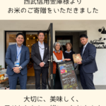 西武信用金庫様より寄贈されたお米を、結の子ども食堂の前で受け取る様子の画像_トップページ用