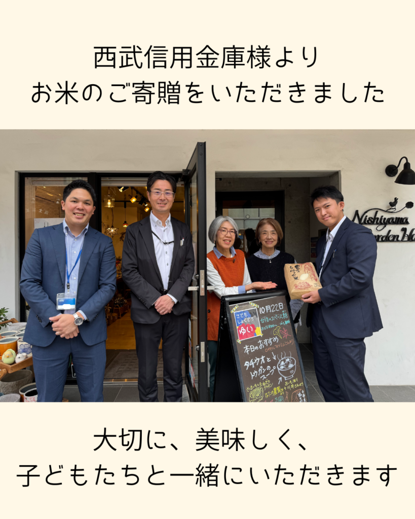 西武信用金庫様より寄贈されたお米を、結の子ども食堂の前で受け取る様子の画像_トップページ用